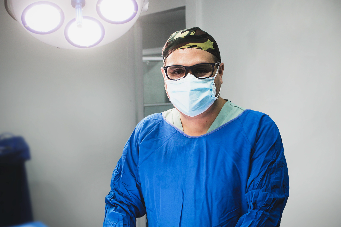 Retrato de un profesional médico con uniforme azul en su consultorio
